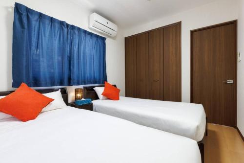 two white beds in a room with blue curtains at 庭付き一棟貸 ビーチまで3分 宇利島車で7分 最大8人 Luana house in Nago
