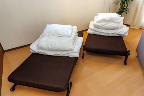 two trunks with white sheets on them in a room at 庭付き一棟貸 ビーチまで3分 宇利島車で7分 最大8人 Luana house in Nago