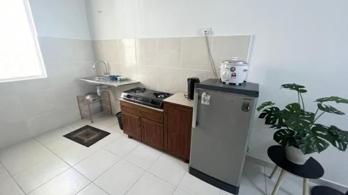 a small kitchen with a stove and a sink at Homestay Near Plaza Tol Bandar Ainsdale in Labu