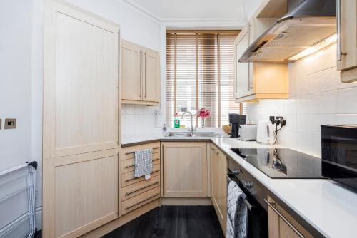 a kitchen with wooden cabinets and white counter tops at Leicester Square Apartment in London