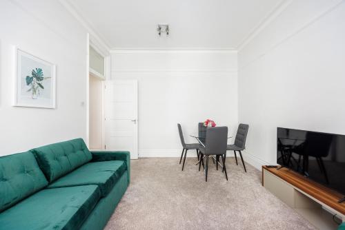 a living room with a green couch and a table at Leicester Square Apartment in London