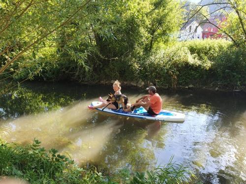 a man and a woman and a dog on a raft in a river at Burgenwelt im wilden Süden in Münsingen