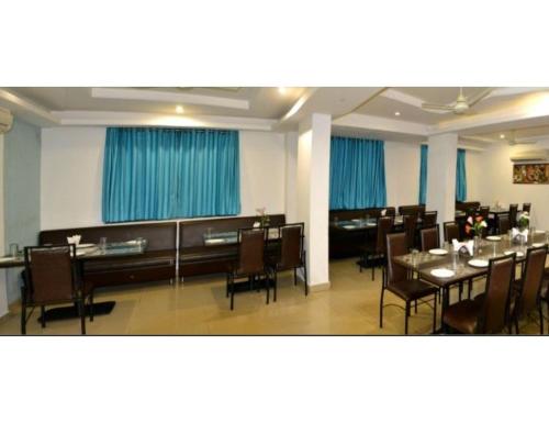 a dining room with tables and chairs and blue curtains at Hotel Flora Inn, Nagpur in Nagpur