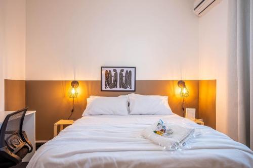 a bedroom with a large white bed with two lights at Apto a 300 metro da praia - WIFI 200MB - Cozinha equipada - Ar condicionado in Rio das Ostras
