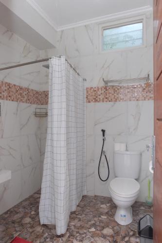 y baño con aseo y cortina de ducha. en Shoreside Semat Villa and Flat en Jepara