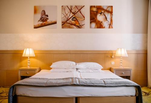 a bed in a bedroom with three pictures on the wall at Hanza Pałac Wellness & SPA in Warlubie