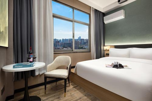 a hotel room with a bed and a table and a window at Unitour Hotel, Xiangxiang Dongfeng Square in Xiangxiang