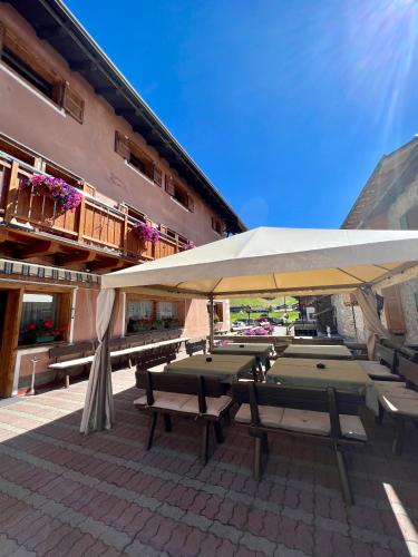 a group of picnic tables under a white umbrella at Hotel Adele in Livigno