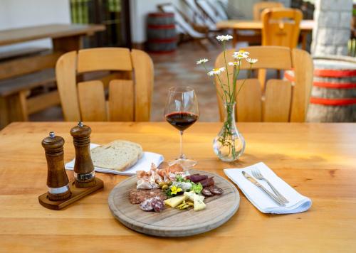 een houten tafel met een bord eten en een glas wijn bij EkoTurizem Hudičevec in Postojna