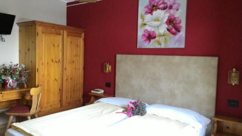 a bedroom with a white bed and a red wall at Hotel Adele in Livigno