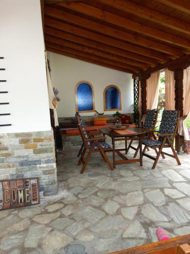 a patio with chairs and a table on a stone floor at Poly's Sea Side House in Koropi