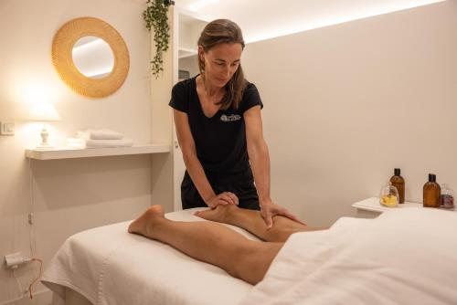 a woman getting a mans legs on a bed at Hôtel & Espace Bien-être La Maison du Lierre in Biarritz
