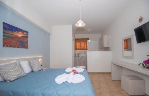 una camera da letto con un letto blu con un fiocco bianco di Baywatch Apartments on the Beach ad Amoudi