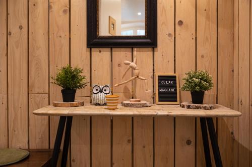 a table with plants and a mirror on a wooden wall at Hôtel & Espace Bien-être La Maison du Lierre in Biarritz