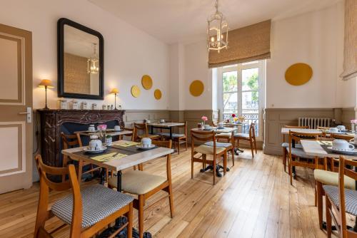a restaurant with tables and chairs and a mirror at Hôtel & Espace Bien-être La Maison du Lierre in Biarritz