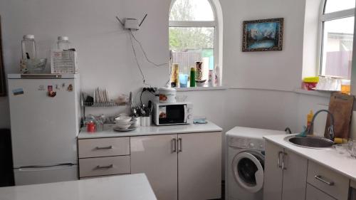 a kitchen with a refrigerator and a washing machine at Nomadstan CAPSULE Hostel in Karakol