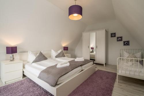 a bedroom with a white bed and a crib at FeWo 1 ''Am Rodelberg'' in Priborn