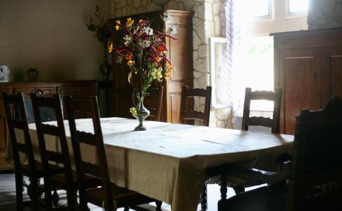 une table de salle à manger avec un vase de fleurs dessus dans l'établissement Eco-Gîte du Moulin de Dun, Ariège, à Dun