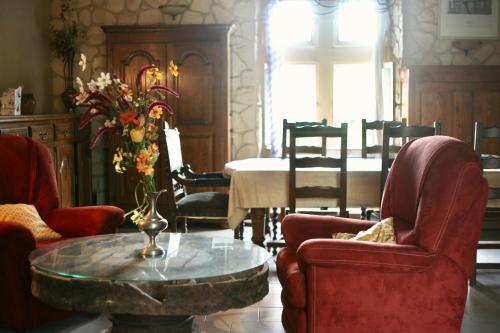 - un salon avec des chaises et une table ornée d'un vase de fleurs dans l'établissement Eco-Gîte du Moulin de Dun, Ariège, à Dun