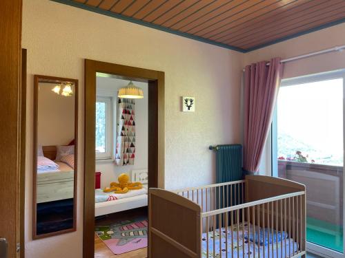 ein Babyzimmer mit einem Kinderbett und einem Spiegel in der Unterkunft Landhaus Schönblick in Radenthein