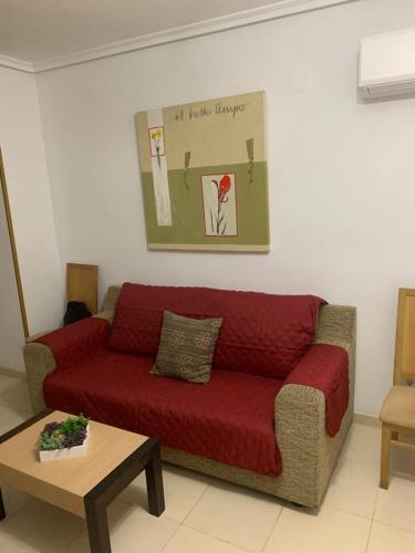 a red couch in a living room with a table at Cala Blanca on the beach in El Borseral