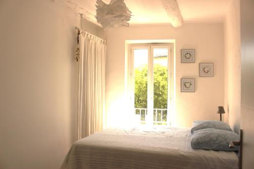 - une chambre avec un lit et une fenêtre dans l'établissement Joli appartement avec balcon au coeur de Forcalquier, à Forcalquier