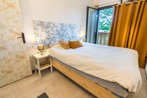 une chambre avec un grand lit avec une fenêtre dans l'établissement Cosy Villa Patio, à Seignosse