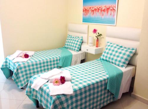two beds in a small room with flowers on them at Hotel Shakey in Santo Domingo