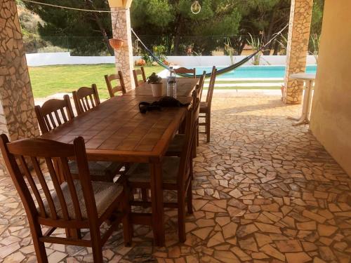 een houten tafel en stoelen op een patio met een zwembad bij Moradia penina v3 in Portimão