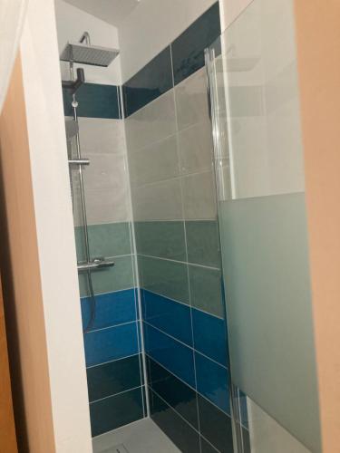 a shower in a bathroom with blue tiles at LES ROCHES gîte in Corme-Royal