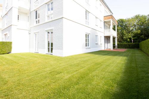 a large grassy yard in front of a white building at Duinhof in Cadzand-Bad