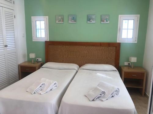 two beds in a bedroom with white sheets and towels at Relax Playa Son Bou, Menorca in Son Bou