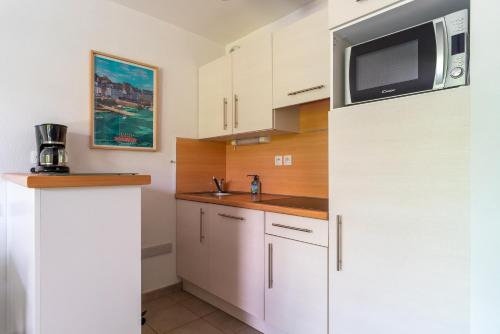a kitchen with white cabinets and a microwave at Le Kichen - Appt proche de la plage in Bénodet