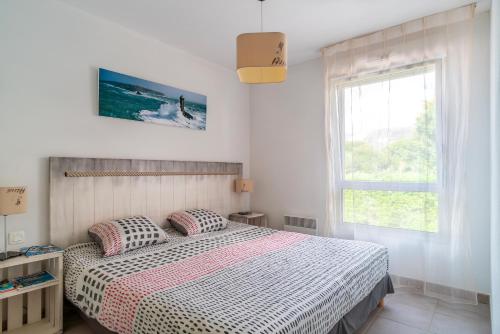 een witte slaapkamer met een bed en een raam bij Le Kichen - Appt proche de la plage in Bénodet