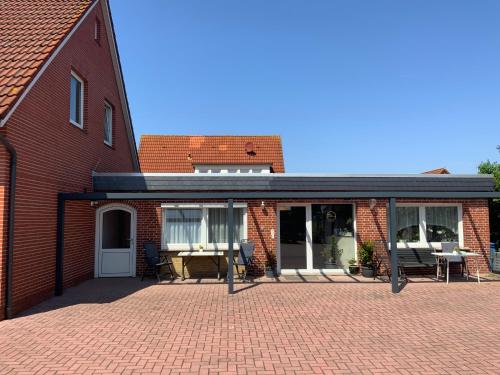 a brick house with a patio with a table and chairs at Pension Deichblick 2 in Norddeich