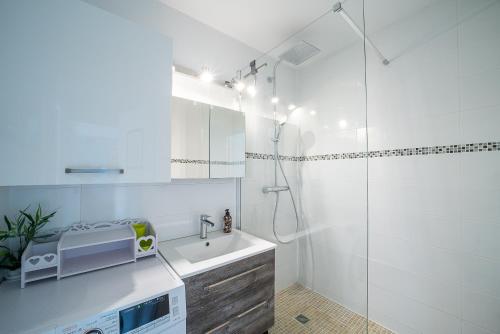 La salle de bains blanche est pourvue d'un lavabo et d'une douche. dans l'établissement La Casa de Cricri - Appartement climatisé, à Perpignan