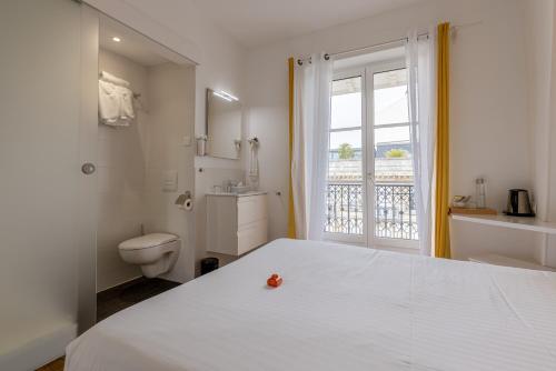 a bedroom with a bed and a toilet and a window at Hôtel & Espace Bien-être La Maison du Lierre in Biarritz
