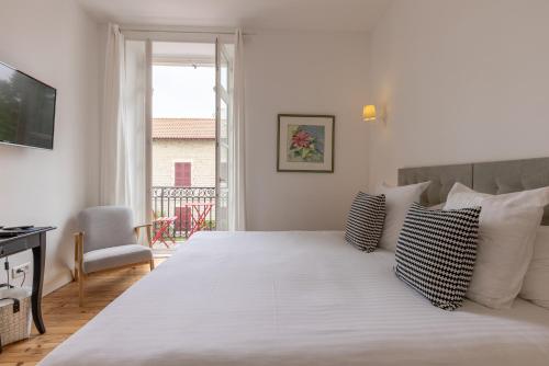 a white bedroom with a large white bed with pillows at Hôtel & Espace Bien-être La Maison du Lierre in Biarritz