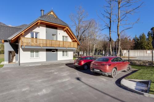 two cars parked in a parking lot in front of a house at Chic Apartments with Finnish Sauna and Jacuzzi in Kranjska Gora