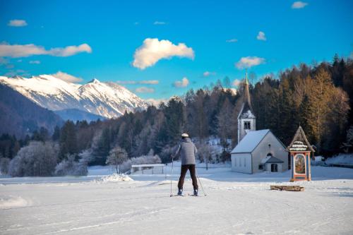 a person on skis in the snow next to a church at Chic Apartments with Finnish Sauna and Jacuzzi in Kranjska Gora