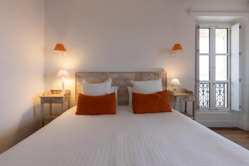 a bedroom with a large white bed with orange pillows at Hôtel & Espace Bien-être La Maison du Lierre in Biarritz