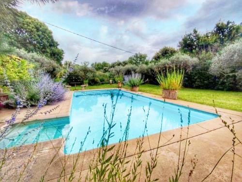 uma piscina no meio de um jardim em Maison au Calme avec Piscine en Provence em Carpentras
