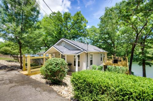 a small white house with a wooden porch at Dock and Boat Slip Lakefront Osage Beach Home! in Osage Beach