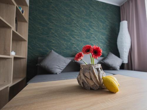 Eine Vase mit roten Blumen und einer Zitrone auf dem Tisch. in der Unterkunft Dream Team Bocianowo in Bydgoszcz