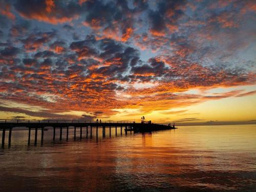 a pier on the water with a sunset at Great Water and Sunset Views Kingfisher Bay in K'gari Island (Fraser Island)