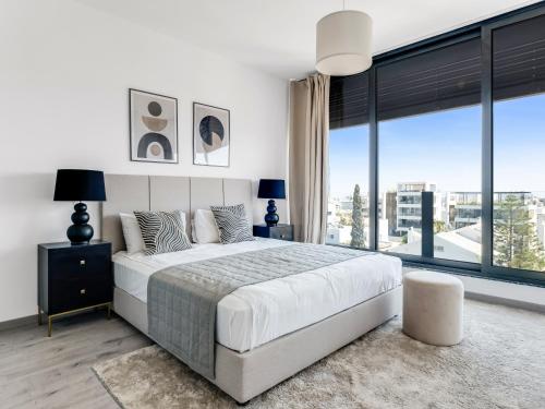 a bedroom with a large bed and a large window at Sanders Park Central Residences in Limassol