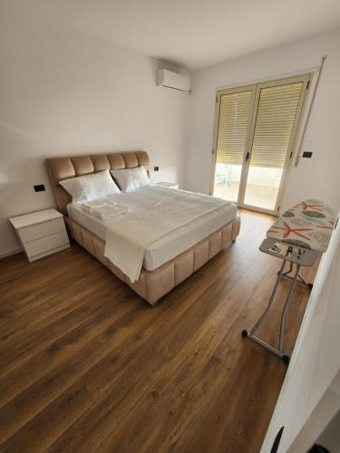 1 dormitorio con 1 cama grande y suelo de madera en Cloud 10 Apartment, en Vlorë