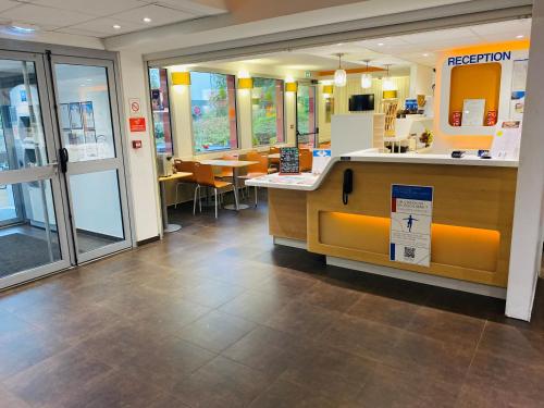 a restaurant with a counter and tables and chairs at ibis budget Noyon in Noyon