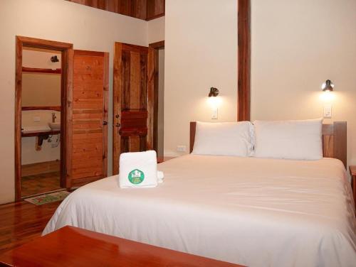 a bedroom with a large white bed with a towel on it at La Casa de Cecilia Mindo in Mindo