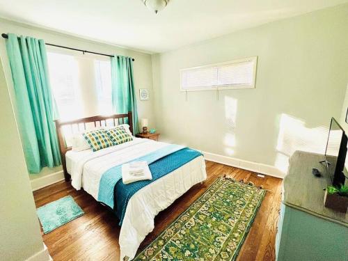 Schlafzimmer mit einem Bett mit blauen Vorhängen und einem Teppich in der Unterkunft Cozy bungalow with Grill near Crossplex in Birmingham
